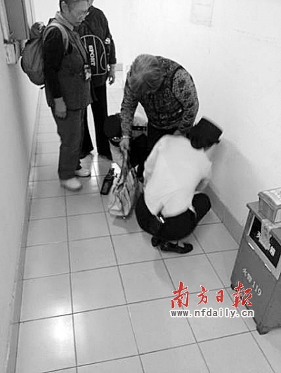 地铁站工作人员为阿婆擦拭裤子上的脏物。