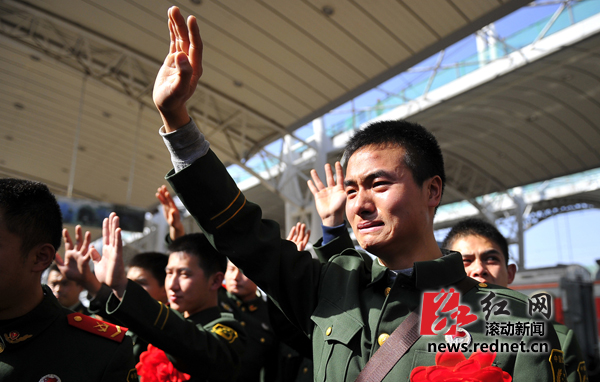 11月25日,一名退伍战士在张家界火车站站台上向战友们含泪挥手道别.