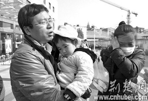 图为：3岁的妞妞依偎在爸爸怀中，一旁的妈妈黯然泪下