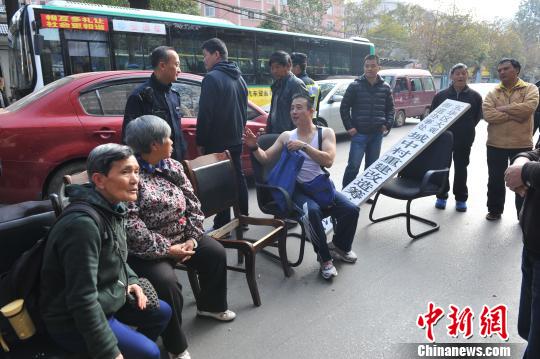 情绪激动的民众搬椅子坐在了马路中间，造成交通拥堵。 任东 摄