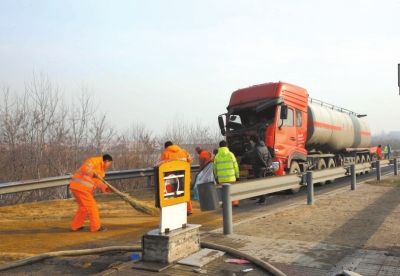 肇事油罐车前脸受损严重，工作人员正在清理油污。