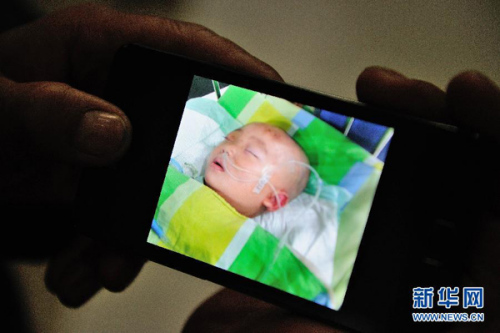 　　12月6日，受害男婴原原的爷爷让记者看他用手机拍摄的原原在重症监护室治疗的照片。原原入院时被诊断为重型颅脑损伤、蛛网膜下腔出血、右側顶部分离性骨折、头皮挫裂伤、肺挫伤、左侧气胸、右侧眼眶外侧壁骨折等多处内外伤。据警方调查，肇事女孩自述把原原放到栏杆上，导致他坠楼，后来又到楼下灌木丛中将坠楼的原原挪至七八米远的小道上。目前原原家属已经提起民事诉讼。新华社记者 李健 摄