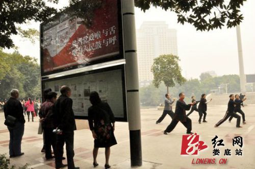 10月22日，娄星广场阅报栏前，市民或阅报或健身，一派和谐城市景象