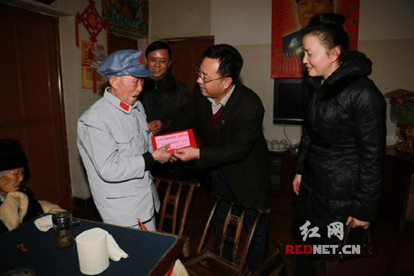 张家界市国税局局长黄成（右二）将慰问金送给彭老（左一）手中，陪同慰问的市局总经济师刘英（右一）