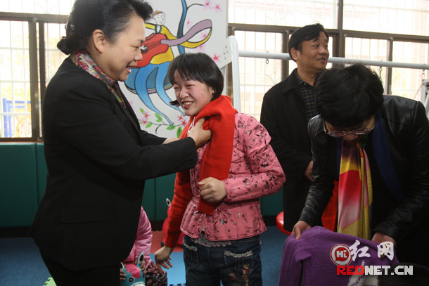湖南省妇联主席肖百灵在长沙市第二社会福利院慰问孤残儿童,并帮孩子们穿上爱心毛衣。