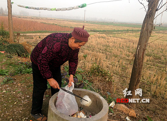 村民陈娭毑将老伴不小心扔掉的塑料餐具捡回来。