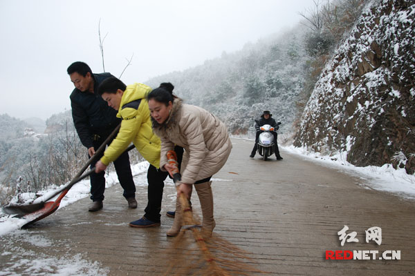 周慈英带着老公、儿子，打扫浏阳乡村公路上的积雪，方便车辆人员通行。