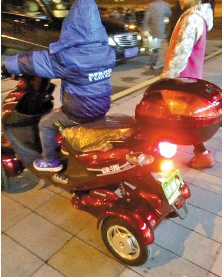“土豪”小男孩正骑着电动车，旁边站着“女友”(网图)