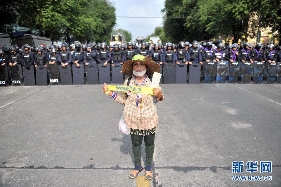 　　2月18日，在泰国首都曼谷的总理府附近，一名反政府示威者站在防暴警察前。当日，泰国警方出动2.5万警力，对总理府、民主纪念碑、能源部、内政部、政府综合办公楼等五个地点附近的集会示威者实施驱逐，并疏通交通，以便政府人员尽快恢复正常工作、学校尽快复课。当天的冲突造成警察和示威者共4人死亡、64人受伤。新华社记者高健钧摄 