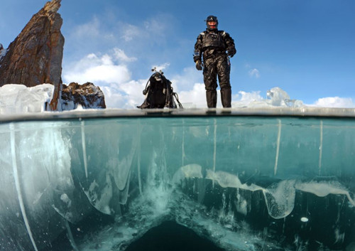 站在厚厚冰层之上的潜水者。