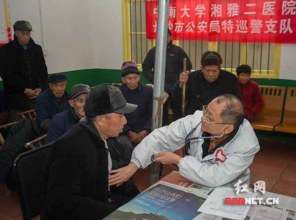 中南大学湘雅二医院老干病房的李友元教授[右一]正在为敬老院的老人们作身体检查。