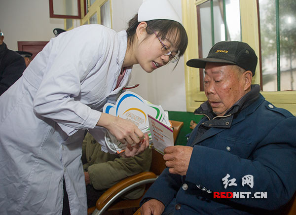 一位年轻护士向老人发放健康知识宣传小册子，并细心地为老人进行讲解。