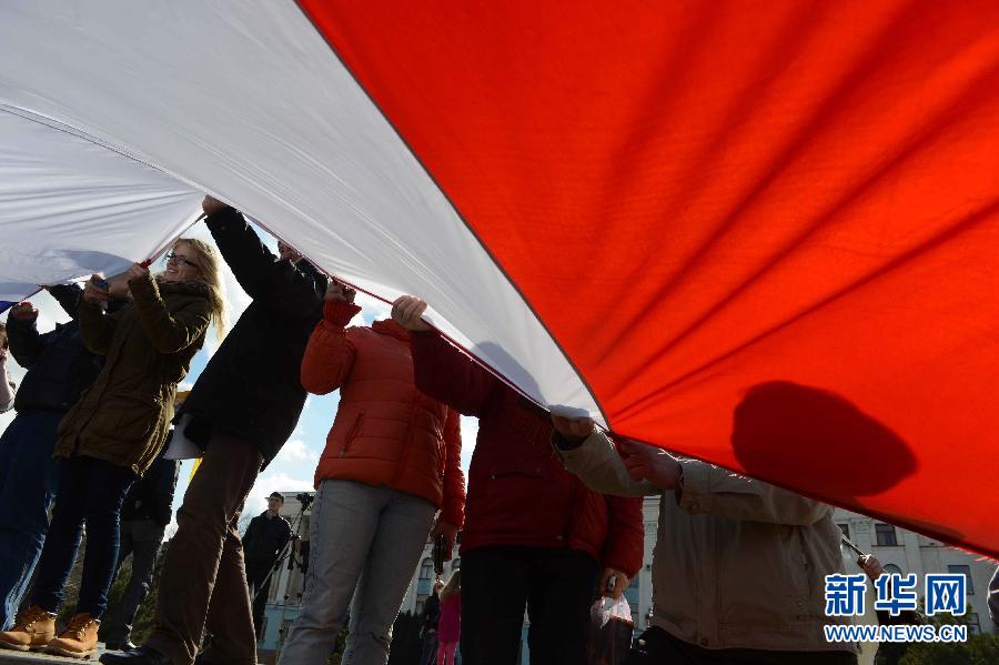 3月18日，乌克兰克里米亚辛菲罗波尔市的列宁广场，人们手持巨型克里米亚地区旗帜庆祝加入俄罗斯联邦。俄罗斯总统普京18日在克林姆林宫同克里米亚及塞瓦斯托波尔代表签署条约，允许克里米亚和塞瓦斯托波尔以联邦主体身份加入俄罗斯联邦。　　新华社记者沙达提摄