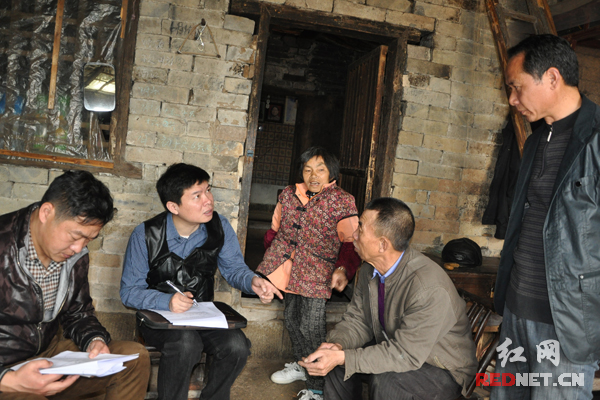 平江县国税局党组书记、局长杜光武(左二)在询问贫困户的基本情况。
