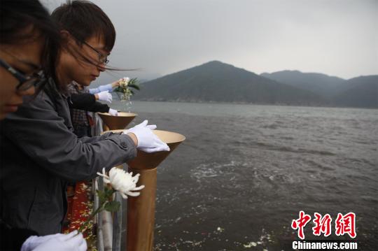 图为18具骨灰在家乡泥土和五彩鲜花的伴随下由其亲人撒向大海　严初　摄src=