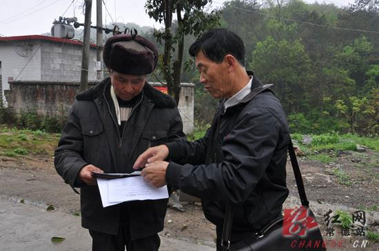 正当采访时，一村民（左）找到郑家贤（右），将一沓资料交给他让其代理办证