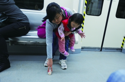 4月20日，长沙地铁2号线，小朋友喝完酸奶后直接把瓶子扔在地上，其母亲立刻捡起（右图）。记者唐俊摄