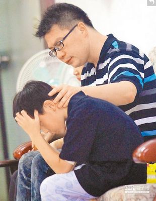 陈瑞琴开车误闯淹水地下道溺毙，死者丈夫强忍悲痛，不断地安抚孩子情绪。（来源 台湾《中国时报》）