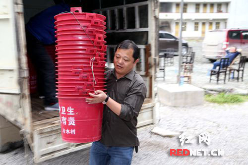 永顺县民政局党组书记、局长李明正在搬运该局为冷水村配发的垃圾桶