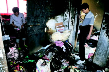 20日,起火的房子里一片狼藉,整个屋都被熏得黑乎乎的,几名租客正在收拾东西。　见习记者　吕奇　摄