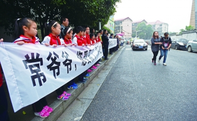 5月22日，长沙市黄兴小学的学生们手举横幅为“金牌义工”常振伟送行。常振伟生前经常在黄兴小学门口护送小学生过马路。新华社 图