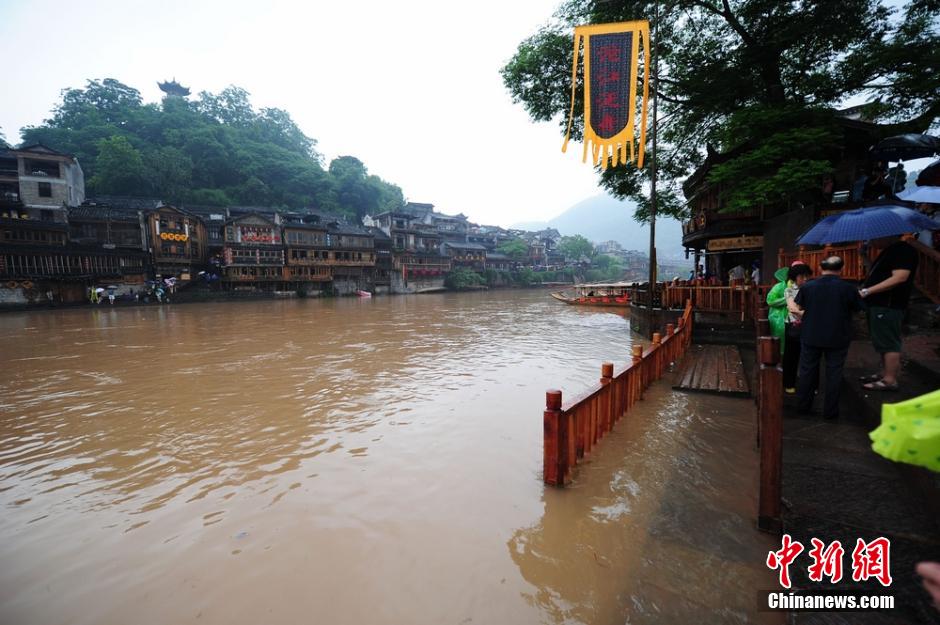 6月2日，连日的暴雨致湖南凤凰古城沱江河水位猛涨，古城内一景点跳岩石墩，几近被淹没。但大水难阻游客出游，水位猛涨的沱江河吸引了有众多游客前来合影留念。 杨华峰 摄