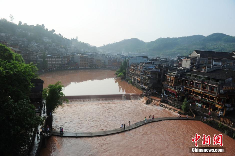 6月2日，连日的暴雨致湖南凤凰古城沱江河水位猛涨，古城内一景点跳岩石墩，几近被淹没。但大水难阻游客出游，水位猛涨的沱江河吸引了有众多游客前来合影留念。 杨华峰 摄 来源：中新网