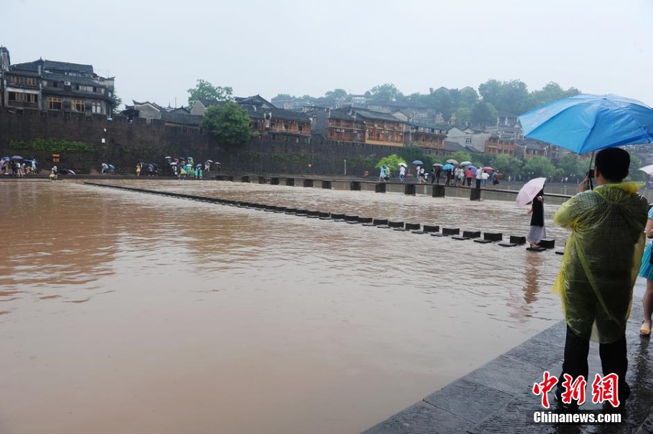 6月2日，连日的暴雨致湖南凤凰古城沱江河水位猛涨，古城内一景点跳岩石墩，几近被淹没。但大水难阻游客出游，水位猛涨的沱江河吸引了有众多游客前来合影留念。 杨华峰 摄 来源：中新网