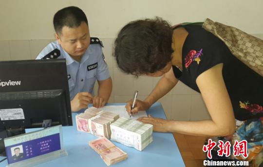 图为受害人刘女士签字领走办案民警追回的现金 谢陈玲 摄