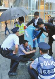 6月13日，成都大慈寺附近，保安张光建和同事及民警帮助坐在雨中的老赵。