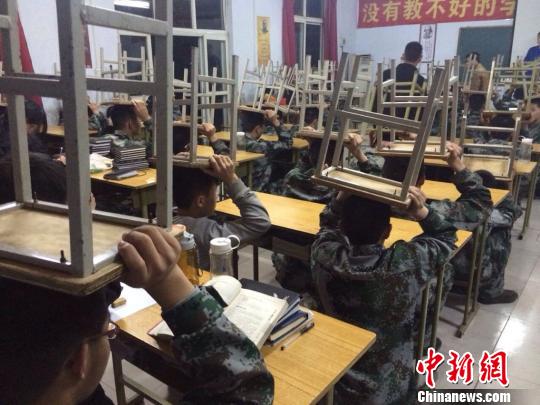 因个别学生坐姿不正，全体同学被罚顶着板凳上课。副校长称“你们坐不好，就让板凳坐你们。”　知情者供图　摄