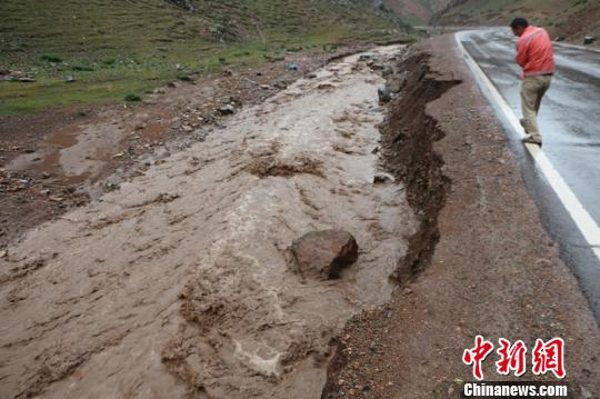 泥石流冲刷半幅道路，抢险人员清理道路堆积物。 木沙尔 摄
