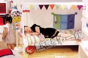 一位婆婆躺在儿童床上，想睡但又怕影响其他顾客购物。