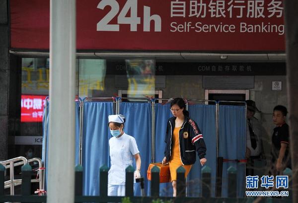 7月18日，医护人员从发生坍塌的大楼走出。新华社记者毛思倩摄