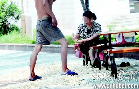 图为：一名妇女包装筷子,一男子从筷子上走过