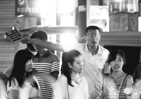 图为：男子举着901纸牌招揽乘客
