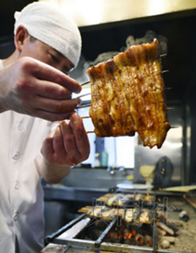 7月29日，东京都中央区的“筑地宫川总店”厨师正在烤制“土用日”食用的鳗鱼