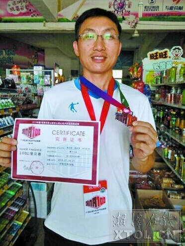 胡思革展示自己的完赛证书、纪念奖牌 （竖戈摄）