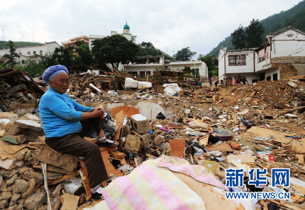 8月9日,在震中云南鲁甸龙头山镇骡马口,李明洁在自家房屋的废墟上休息。新华社记者邢广利摄