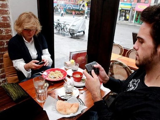 资料图：吃饭时看手机。