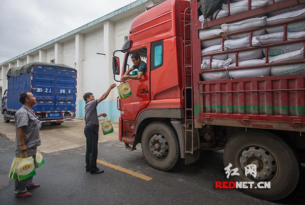  粮库的工作人员向来交售早稻的粮农发放粮食收购政策宣传和慰问用品。