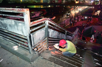  8月20日凌晨，长沙市司门口，工作人员开始切割人行天桥上下台阶及扶手。 
