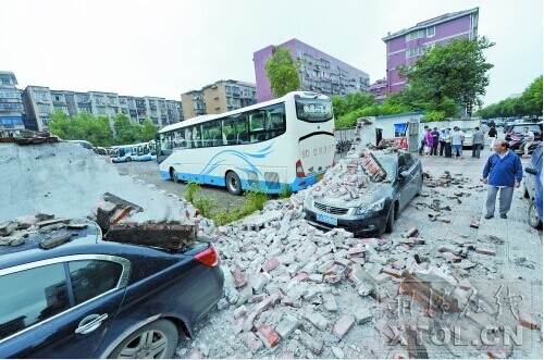 ８月１９日早晨，一名大巴车司机在雨湖区广云路路口附近一处停车场内倒车时，不小心将围墙撞倒，两台黑色小汽车被砸烂。（竖戈 摄）