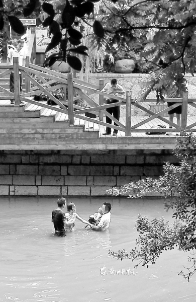 东西河中,董辛元(黑衣)与跳河女子的丈夫一起救人(受访者供图)