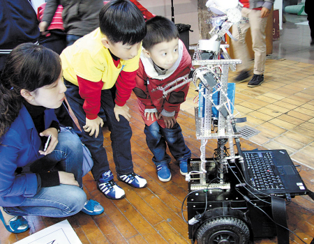 2014年第四届中国教育机器人大赛近日在长开赛，智能机器人吸引小朋友驻足观看。 陈焕明 摄