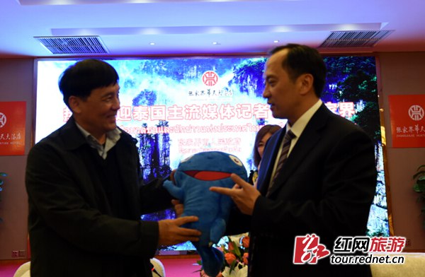 图1:张家界市长许显辉(右)在张家界华天大酒店会见泰国媒体采访团,向客人赠送张家界地理标志产品大鲵玩偶 宋卫红 摄影