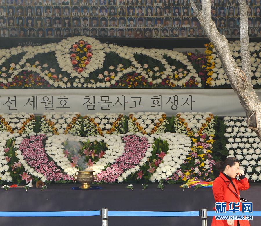 11月11日,一位市民从韩国首尔市厅广场上的“岁月”号沉船事故遇难者祭奠场所经过。