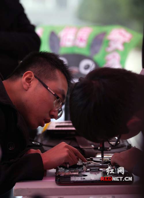 2014年11月29日上午，活动的志愿者们正在打开笔记本电脑后盖，为同学提供清灰服务