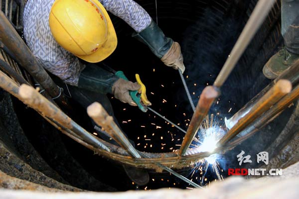 益娄高速公路第十四合同段工人在用电焊固定钢筋笼桩径。