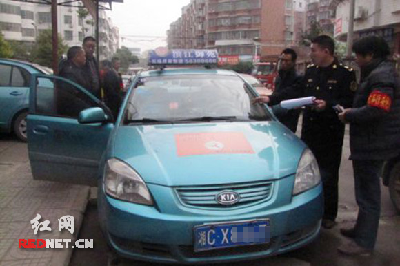 湘乡“文明出租车”考核组的人员正在对湘CX8467的士的车容车貌进行检查打分
